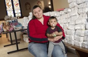 Mother holds baby next to a pile of diapers