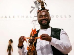 Jaleel Campbell stands with one of his handcrafted dolls