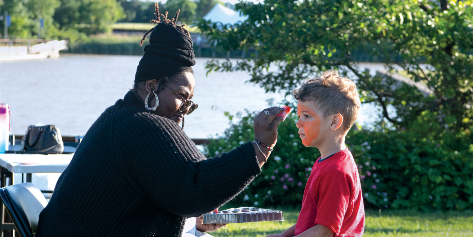 Woman painting a child's face outside