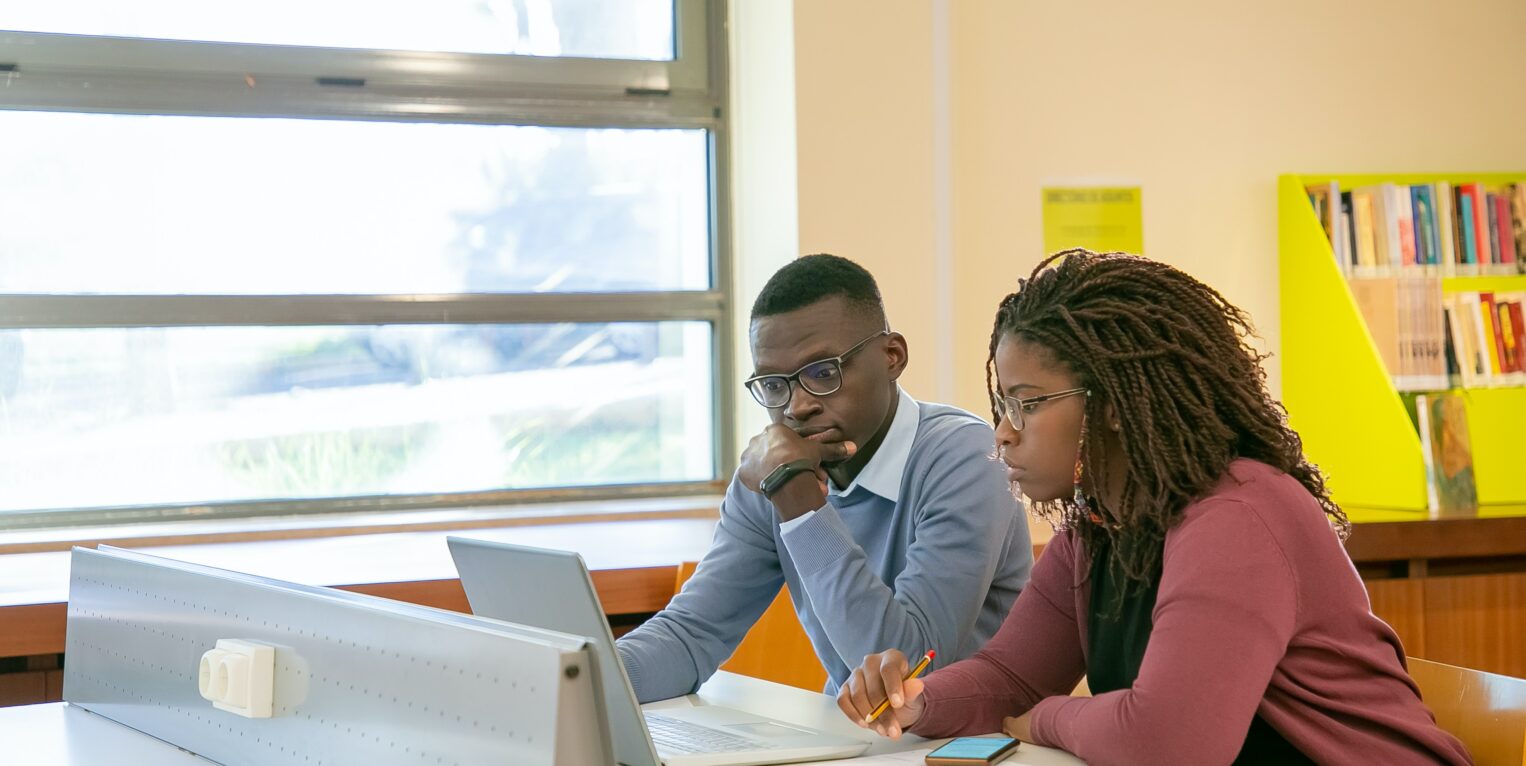 Students sitting around a table using laptops